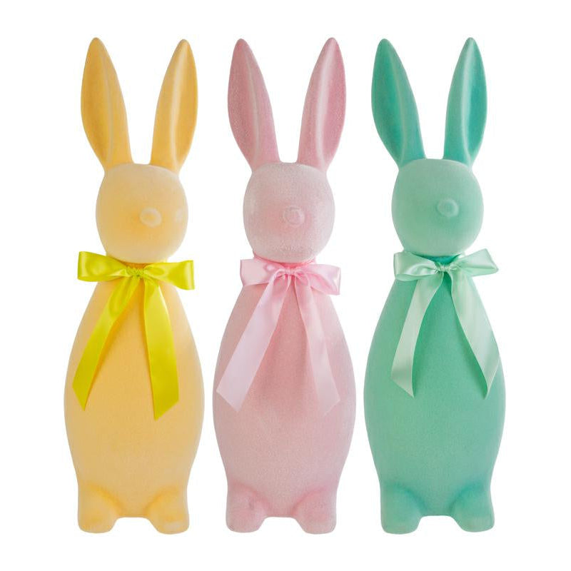 Tris di coniglietti pasquali decorativi del marchio Le Stelle (codice 12224) con finitura floccata effetto velluto. Il set comprende tre varianti di colore pastello: giallo ocra, rosa cipria e verde acqua, ognuna ornata da un fiocco in raso coordinato. Statuine dal design stilizzato e moderno per l'arredamento di Pasqua.