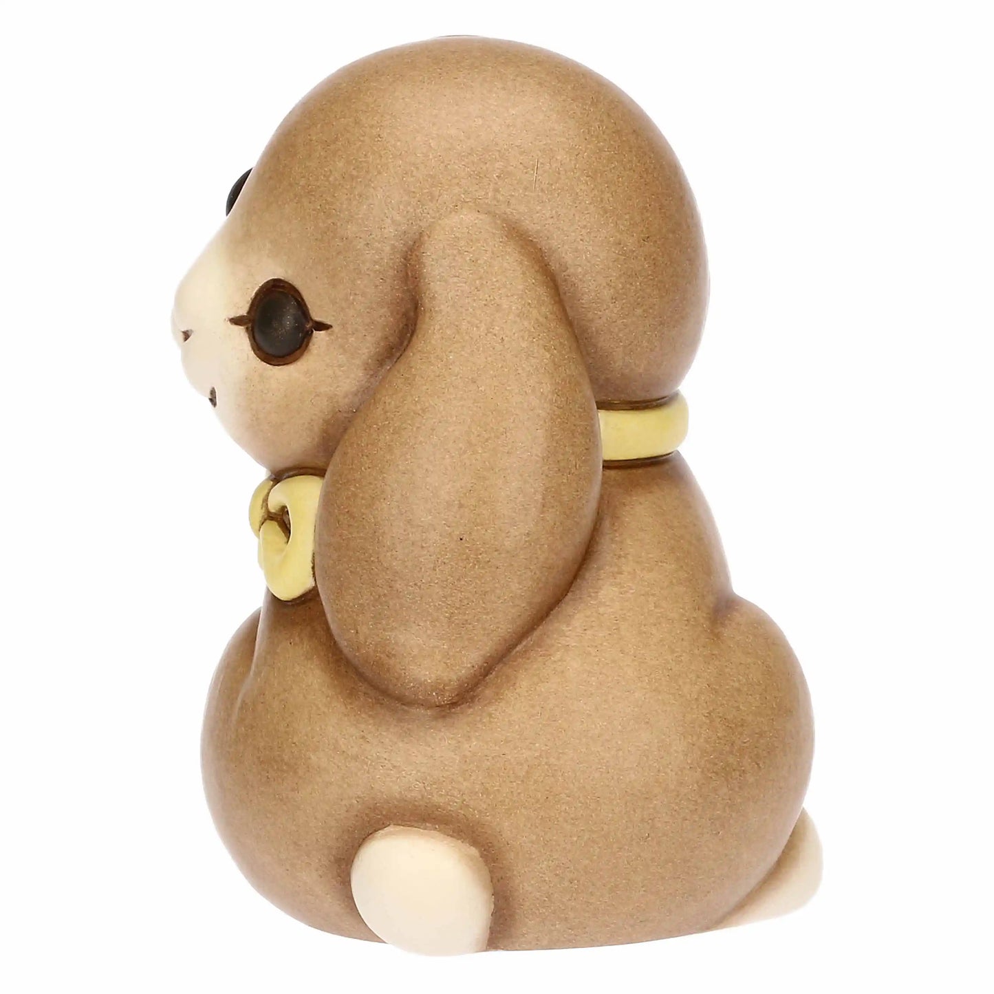 Statuina in ceramica Thun raffigurante il coniglio Roger della collezione Incanto di Pasqua. Il coniglietto, nei classici toni del marrone sfumato, è ritratto seduto con un fiocco giallo al collo e grandi occhi dolci. Iconica decorazione pasquale Thun con finitura opaca e forme morbide.