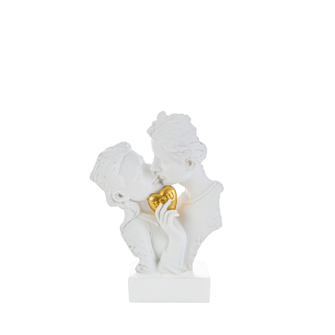 Statuina in resina bianca raffigurante una coppia di innamorati che si baciano tenendo tra le mani un cuore dorato con scritta "I love you", presentata accanto alla sua sacchetto regalo bianco con logo "Le Stelle Bomboniere". Scultura elegante ideale come bomboniera per matrimoni o anniversari, con confezione firmata pronta per il regalo.