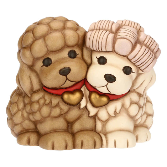 L'immagine mostra una statuetta decorativa che ritrae due cani Barboncini seduti l'uno accanto all'altro in una posa affettuosa, con le teste inclinate che si toccano al centro.