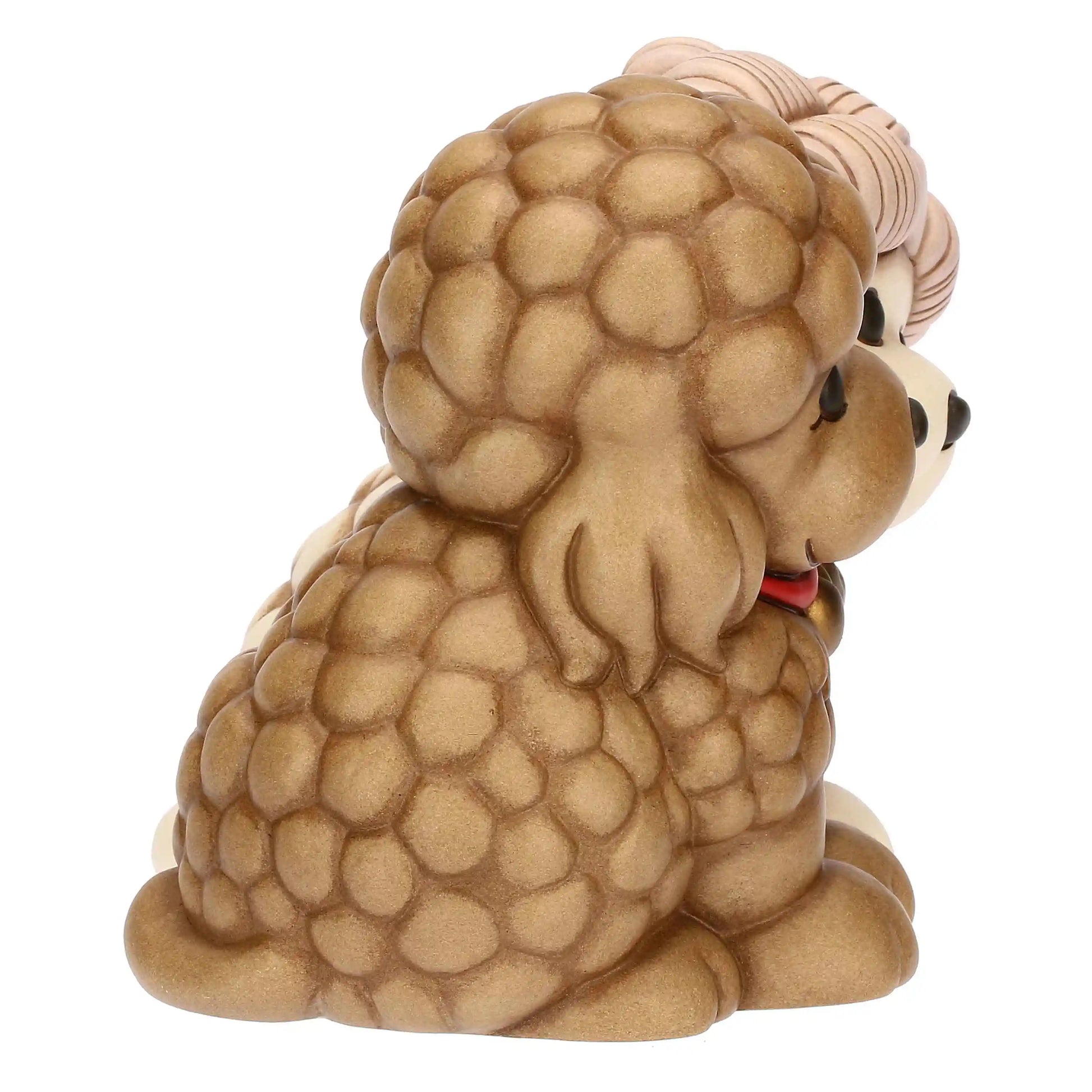 L'inquadratura laterale permette di apprezzare la profondità della scultura e la ricchezza della texture a pompon che avvolge il corpo del barboncino marrone.