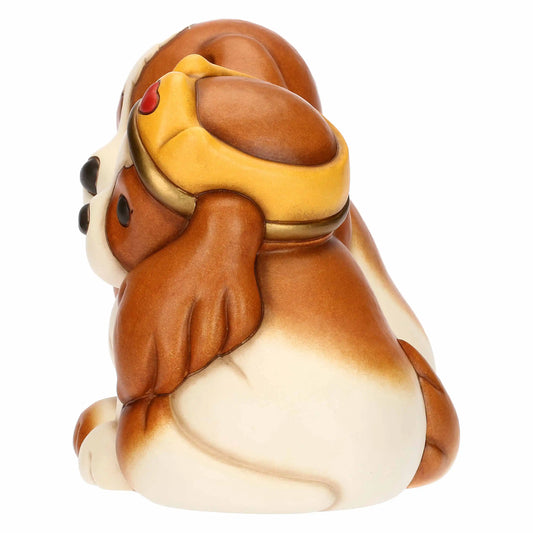 Vista di profilo della statuina dei cagnolini, che mostra la curvatura della corona dorata e le linee morbide e arrotondate della ceramica dipinta nei toni caldi del marrone e del crema.
