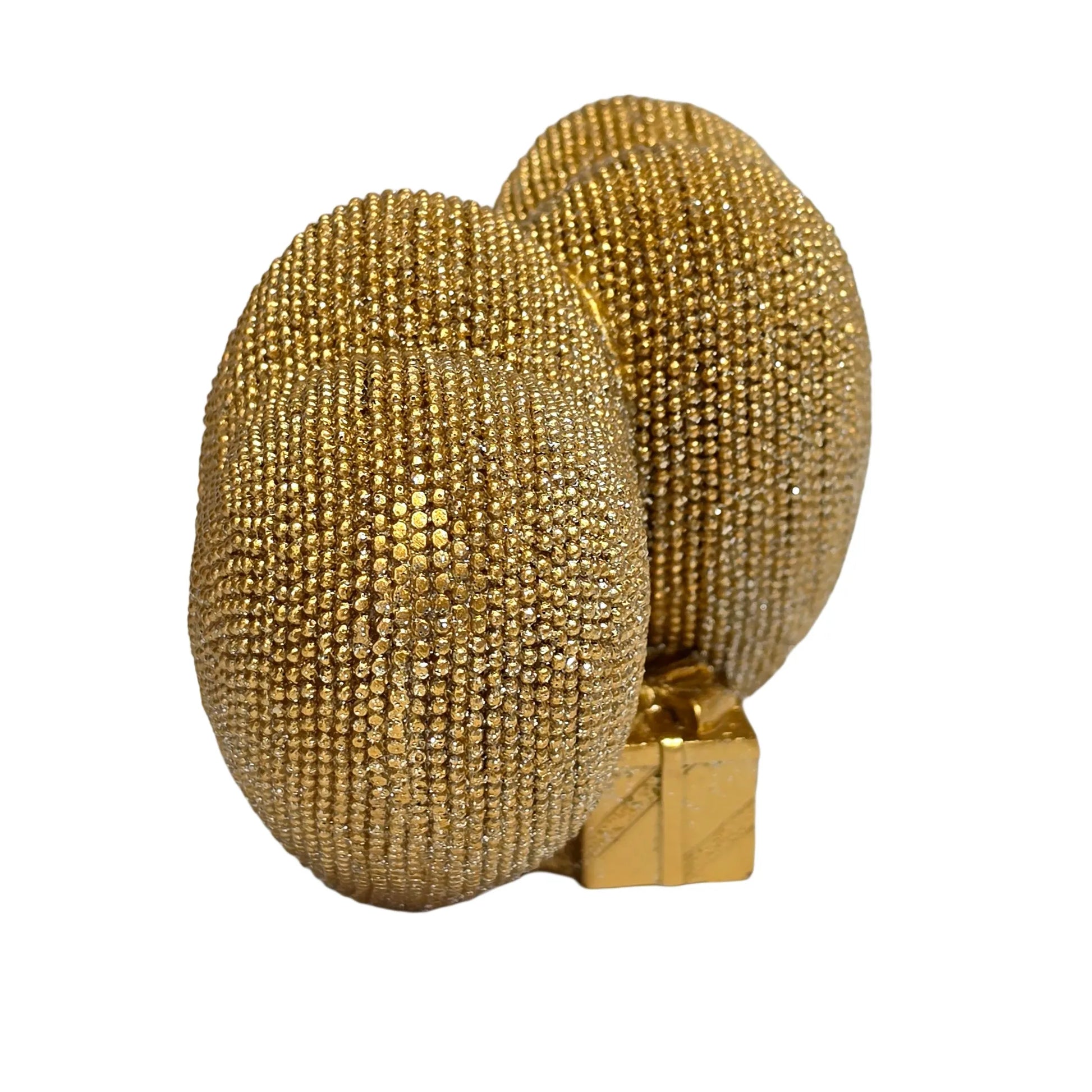 Statuina in resina raffigurante due cuori dorati affiancati, interamente ricoperti di brillantini glitterati, con un piccolo pacco regalo dorato liscio incastonato alla base. Oggetto decorativo firmato Sud Import, ideale come soprammobile romantico o idea regalo per San Valentino e occasioni speciali.