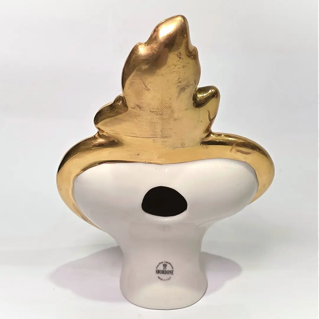 Scultura a forma di Cuore Sacro in ceramica nera lucida, impreziosita da una ricca cornice dorata lavorata a sbalzo e decorata con loghi fashion iconici in oro. Questo esclusivo oggetto d'arredo in stile pop art presenta una fiamma superiore dorata e una base d'appoggio integrata, perfetto per aggiungere un dettaglio di lusso moderno agli ambienti interni.