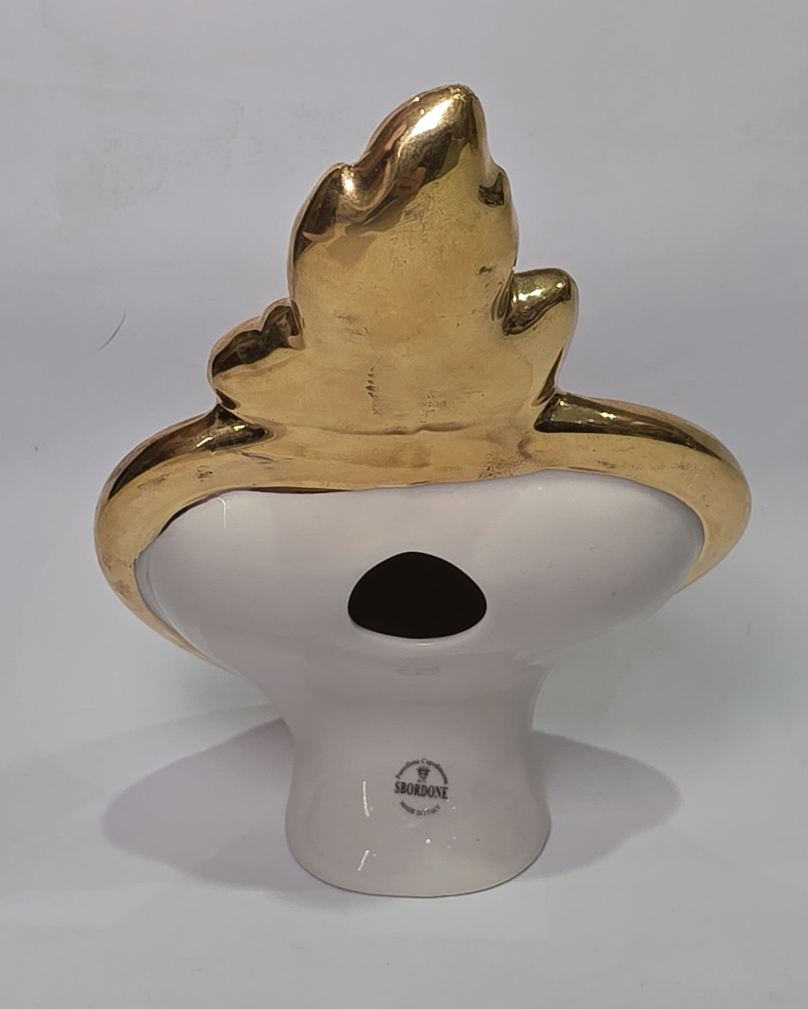 Scultura a forma di Cuore Sacro in ceramica nera lucida, incorniciata da un elegante bordo dorato con decorazioni a rilievo e completata da una fiamma superiore in oro. Questo oggetto di design artigianale con base d'appoggio è un complemento d'arredo raffinato, ideale per arricchire ambienti moderni con un tocco di arte sacra contemporanea.