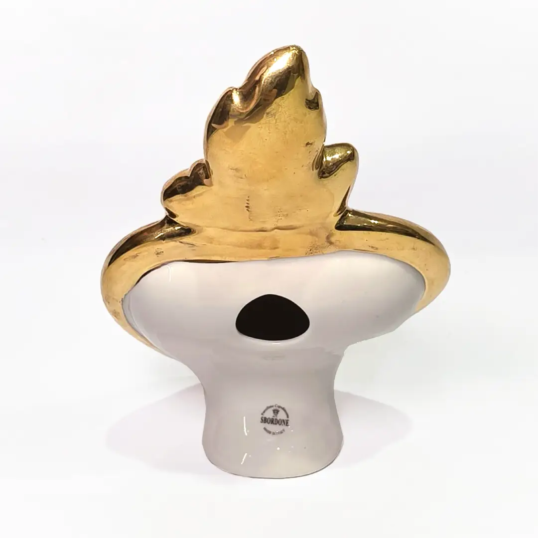 Scultura a forma di Cuore Sacro in ceramica nera lucida, incorniciata da un elegante bordo dorato con decorazioni a rilievo e completata da una fiamma superiore in oro. Questo oggetto di design artigianale con base d'appoggio è un complemento d'arredo raffinato, ideale per arricchire ambienti moderni con un tocco di arte sacra contemporanea.