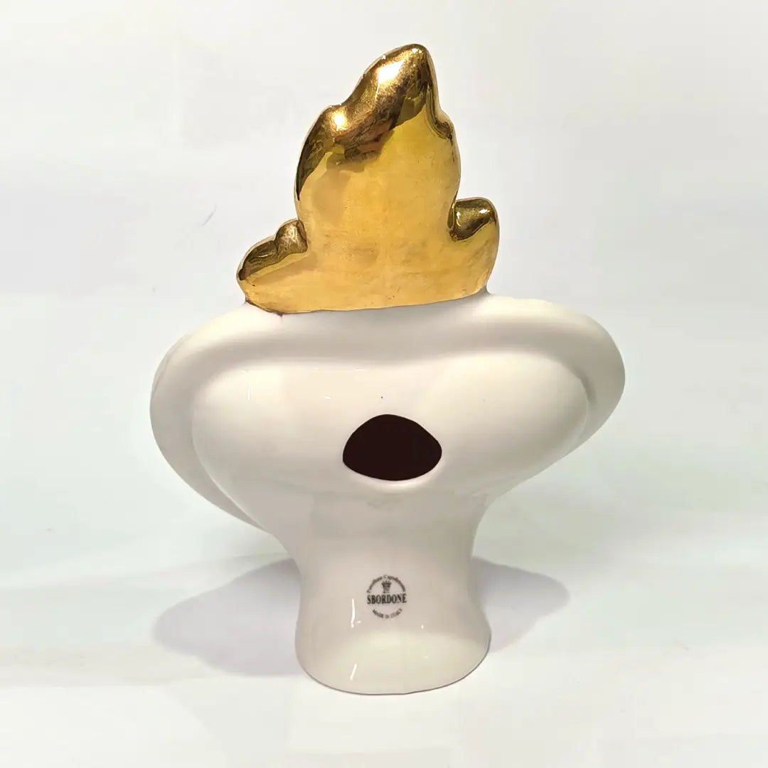 Scultura decorativa a forma di Cuore Sacro in ceramica rossa lucida, arricchita da loghi fashion bianchi e una fiamma superiore dorata. Il design è completato da una cornice bianca perlinata con borchie oro, rendendo questo oggetto un complemento d'arredo pop art unico e di tendenza per la casa.