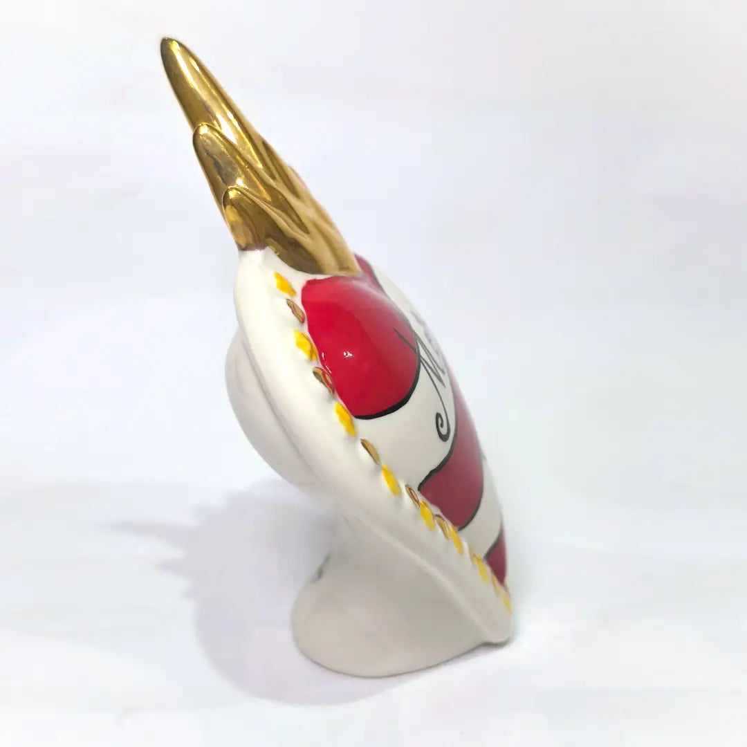 Scultura decorativa a forma di Cuore Sacro in ceramica rossa e bianca lucida, caratterizzata da un design a strisce orizzontali con le scritte "Mom" e "Dad" in corsivo nero. L'oggetto è completato da una corona superiore dorata e una cornice perlinata con dettagli gialli e borchie oro, rappresentando un complemento d'arredo affettivo e originale per la casa.