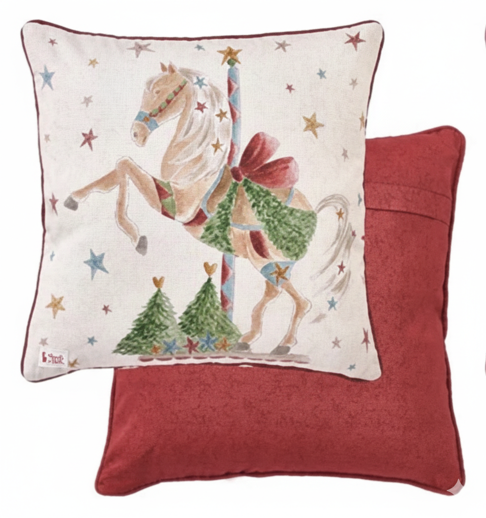 Cuscino natalizio Nuvole di Stoffa "La Giostra di Amelie" (Modello A). Il lato frontale presenta un cavallo da giostra bianco con ghirlanda verde e sella rossa su fondo stellato; il retro è in tessuto rosso pieno.