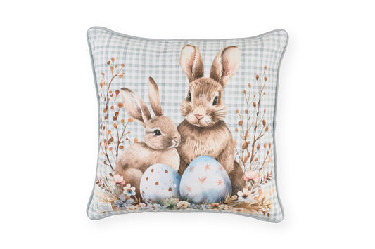 Stampa frontale del cuscino pasquale Nuvole di Stoffa in cotone. Decorazione con illustrazioni di coniglietti, uova colorate e fiori delicati e sfondo a quadretti celesti. Elegante tessile per Pasqua 2026.