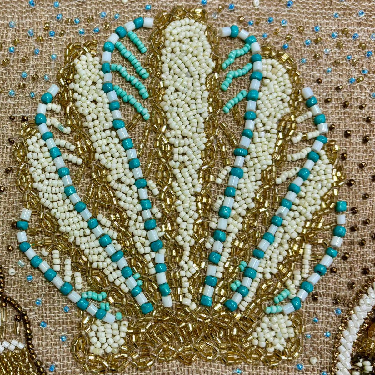 dettaglio del cuscino Blanc Mariclo' linea Maldive in lino naturale color beige. Stampa marina con conchiglie ricamate sabbia e azzurro. Complemento d'arredo per case estive.