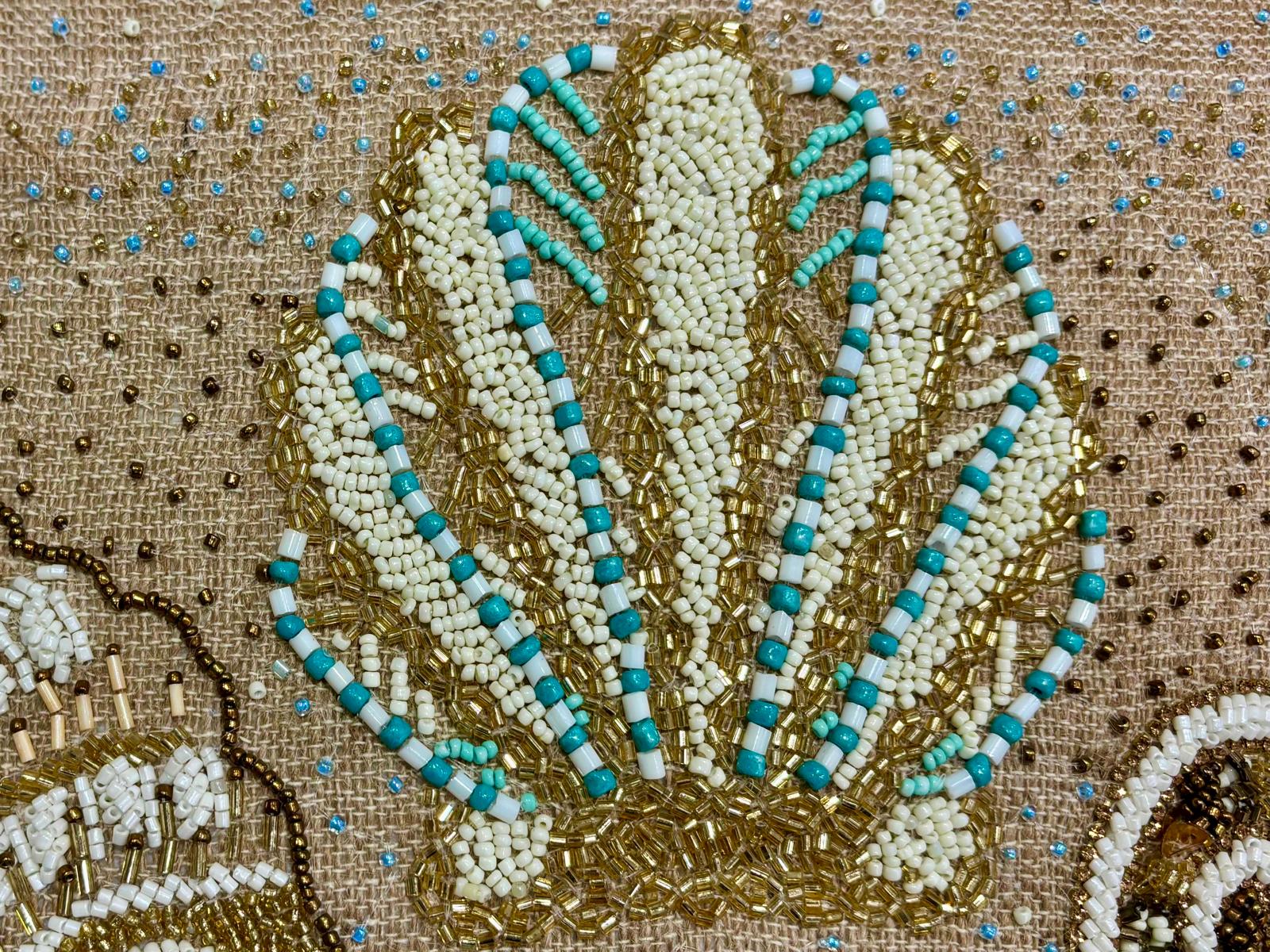 dettaglio del cuscino Blanc Mariclo' linea Maldive in lino naturale color beige. Stampa marina con conchiglie ricamate sabbia e azzurro. Complemento d'arredo per case estive.