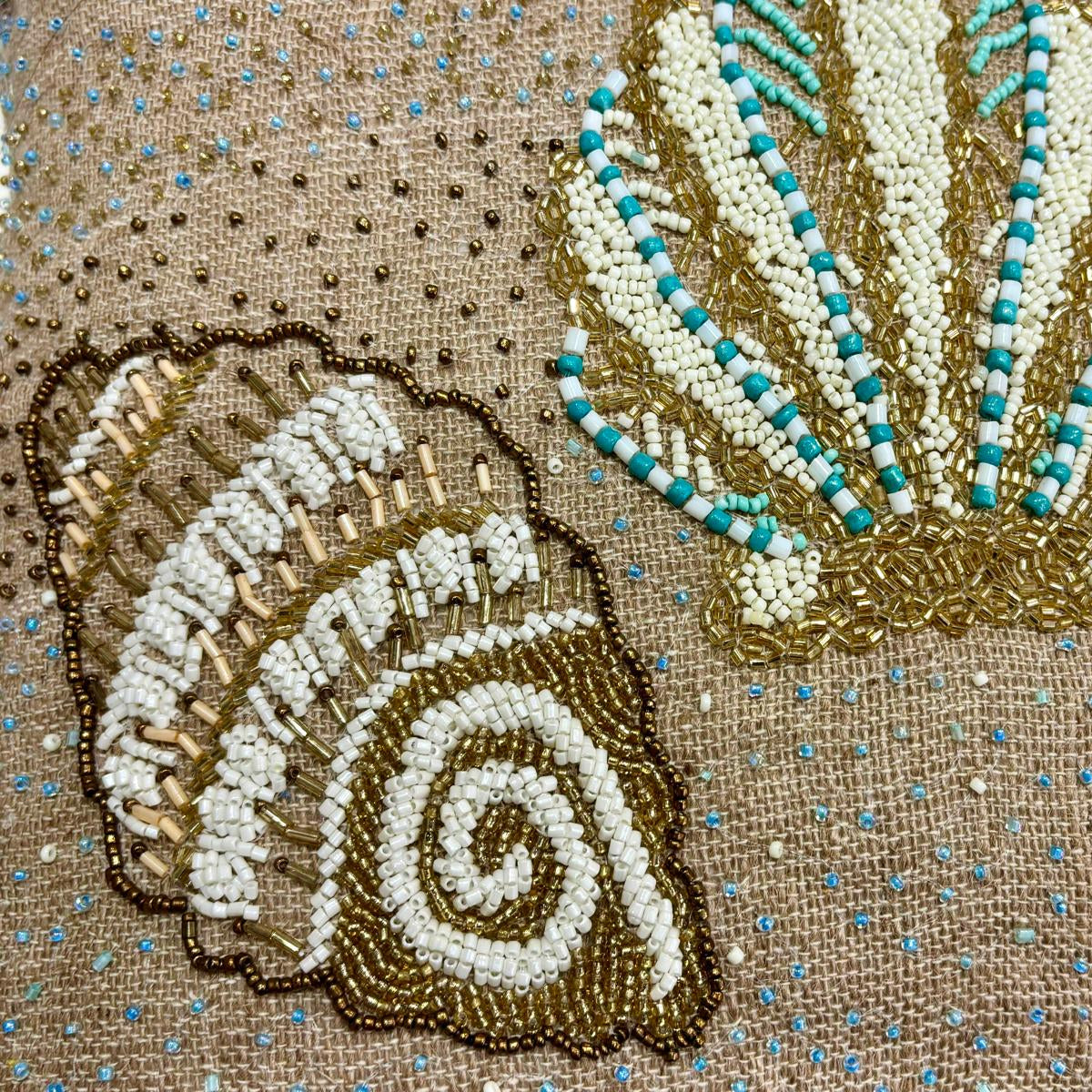 dettaglio del cuscino Blanc Mariclo' linea Maldive in lino naturale color beige. Stampa marina con conchiglie ricamate sabbia e azzurro. Complemento d'arredo per case estive.
