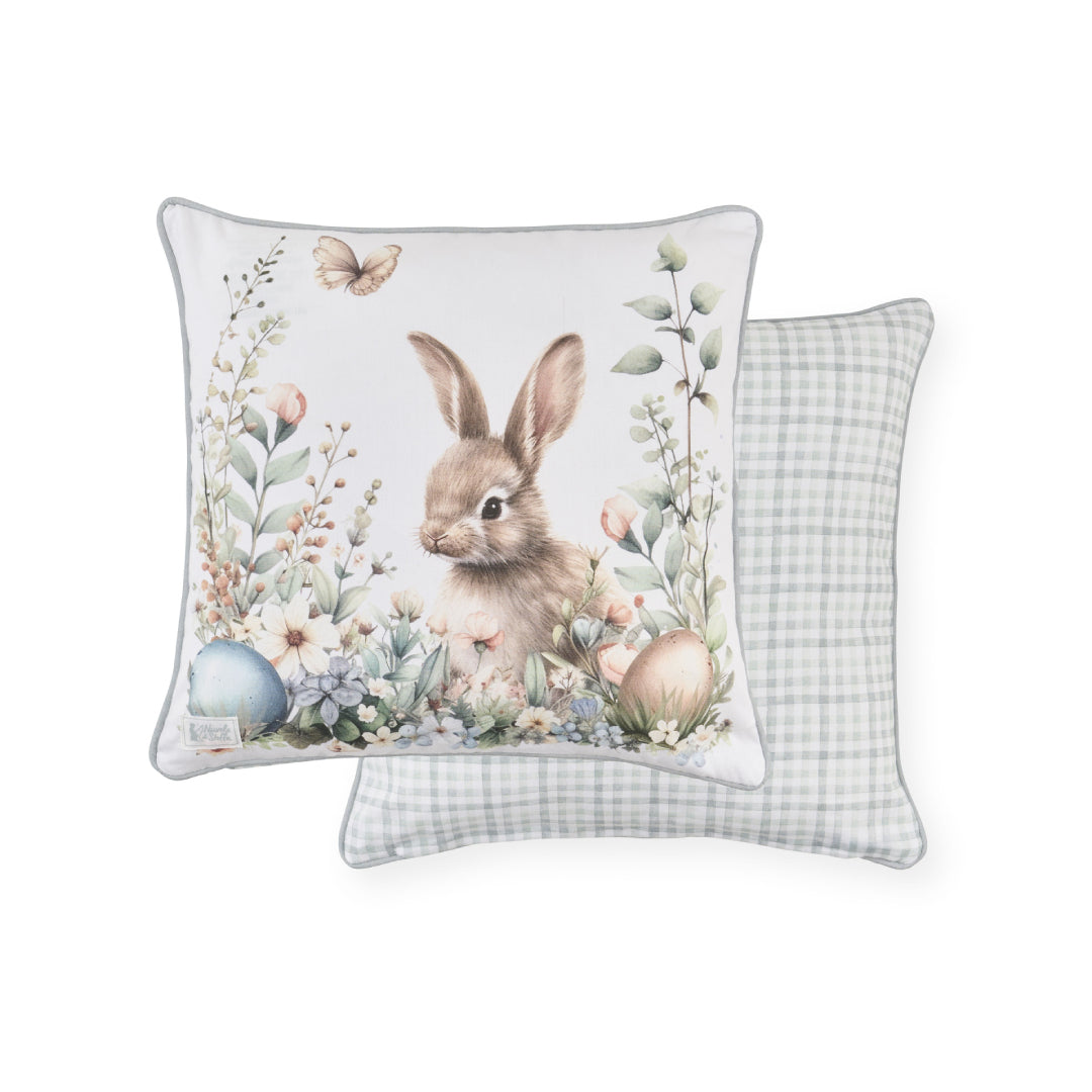 Cuscino pasquale Nuvole di Stoffa in cotone con retro celeste a quadretti vichy. Decorazione con illustrazioni di coniglietti, uova colorate e fiori delicati. Elegante tessile per Pasqua 2026.