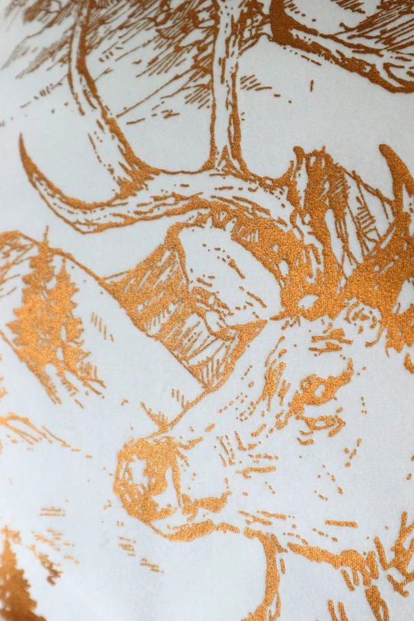 Dettaglio ravvicinato della stampa serigrafica color oro su tessuto bianco. Il disegno mostra i tratti eleganti e definiti della testa di un cervo, tema centrale della collezione.