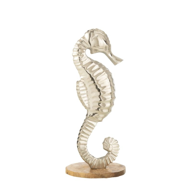 Decorazione a forma di cavalluccio marino in alluminio lucido della linea "Oceano Azul", posizionato su una base circolare in legno chiaro. Questa scultura ornamentale in stile marino è ideale come soprammobile per abbellire mobili, mensole o consolle della zona giorno.