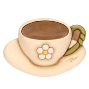 Formella decorativa da parete in ceramica firmata Thun, sagomata a forma di tazzina da caffè con piattino nei delicati toni del beige e del marrone. Questo articolo della linea Country Bloom presenta un fiore bianco a rilievo al centro, un manico verde e il classico marchio Thun dorato sul piattino.