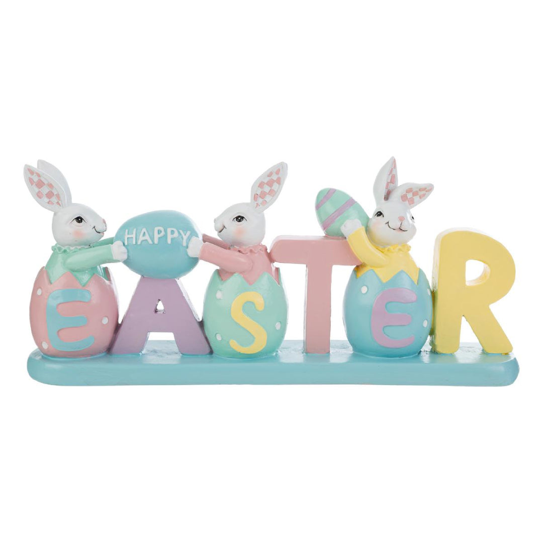 Decorazione pasquale con scritta "EASTER" color pastello e tre coniglietti bianchi. I coniglietti sono inseriti all'interno delle lettere a forma di uovo; i primi due sorreggono un uovo azzurro con la scritta "HAPPY". Statuina decorativa del marchio Le Stelle in resina colorata con dettagli rosa, gialli e verde menta su base azzurra.