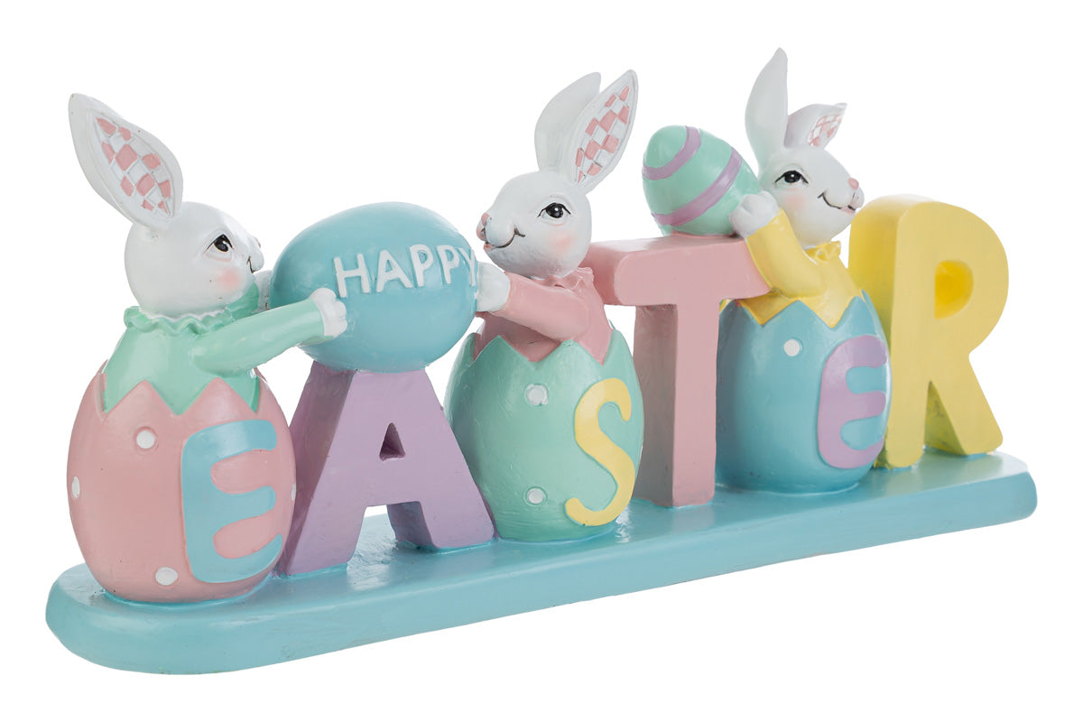 Decorazione pasquale con scritta "EASTER" color pastello e tre coniglietti bianchi. I coniglietti sono inseriti all'interno delle lettere a forma di uovo; i primi due sorreggono un uovo azzurro con la scritta "HAPPY". Statuina decorativa del marchio Le Stelle in resina colorata con dettagli rosa, gialli e verde menta su base azzurra.