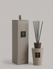 Il Diffusore per Ambienti Cuir Oud EDG è un set di profumazione per la casa composto da una boccetta con finitura intrecciata color tortora, un tappo in legno scuro e bastoncini neri. La scatola regalo coordinata a colonna con scritte dorate racchiude questa sofisticata fragranza legnosa, rendendola un complemento d'arredo perfetto per l'home decor moderno.