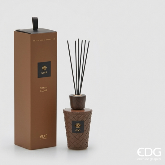 Il Diffusore per Ambienti Cuir Tonka Clove EDG è un set di lusso composto da una raffinata boccetta con rivestimento intrecciato color cuoio marrone, dotata di tappo in legno scuro e bastoncini neri. La confezione regalo a colonna in tonalità coordinata racchiude una fragranza avvolgente, caratterizzata da note di testa all'arancio dolce e miele che sfumano in un cuore di rosa turca e un fondo caldo di fava tonka e vaniglia.