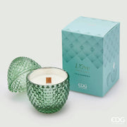 Candela profumata "L'Ove" alla fragranza Fig & Gardenia firmata EDG Enzo de Gasperi, caratterizzata da un elegante contenitore in vetro verde acqua lavorato a rilievo a forma di uovo con coperchio coordinato e stoppino in legno. Questa raffinata candela decorativa di lusso è accompagnata dalla sua confezione regalo in tinta con motivi geometrici, ideale per profumare gli ambienti di casa con stile o come originale idea regalo home decor.