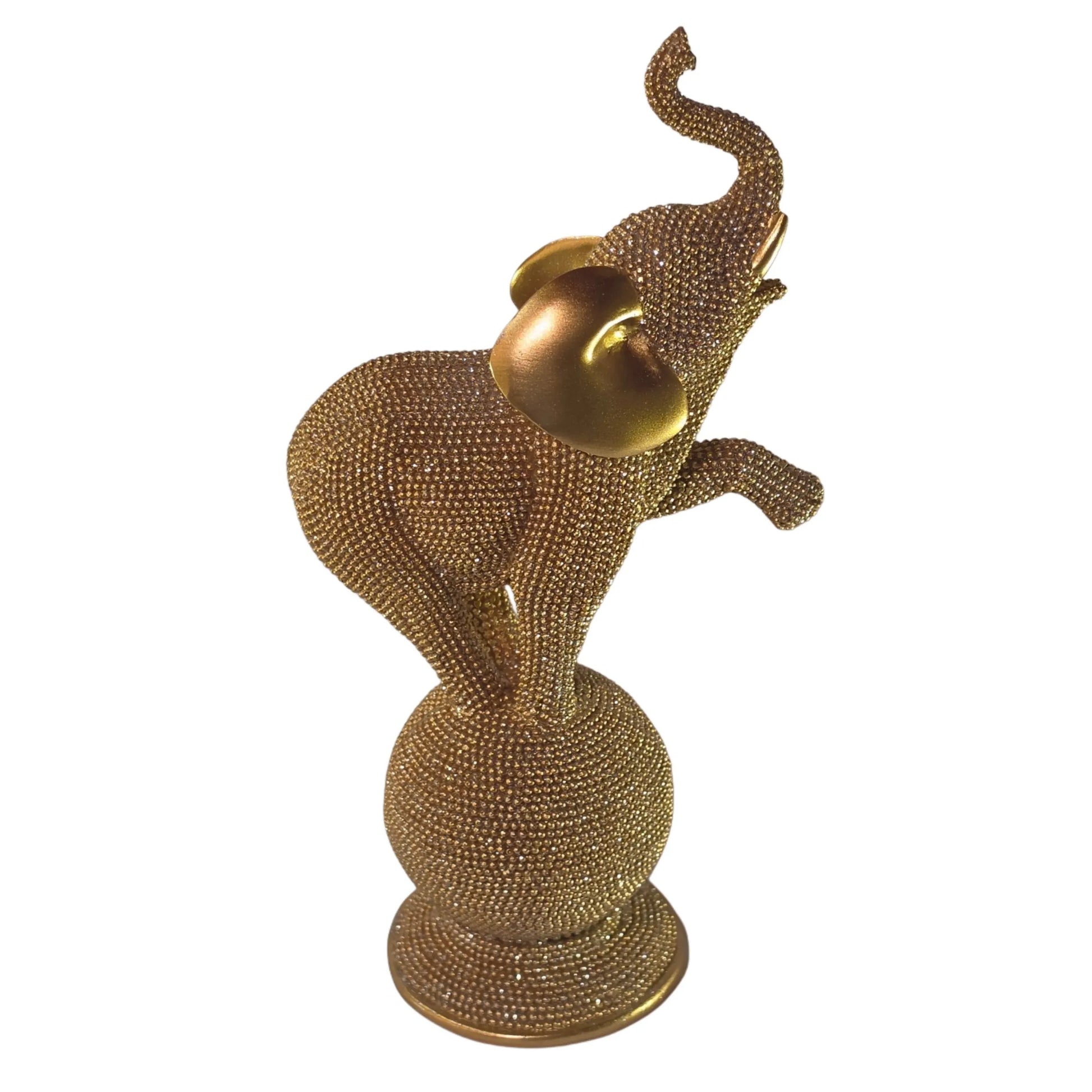 Statuina in resina raffigurante un elefante dorato in equilibrio su una sfera decorativa, con proboscide sollevata e orecchie lisce a effetto metallico, interamente ricoperto di brillantini glitterati. Oggetto decorativo scintillante firmato Sud Import, ideale come soprammobile portafortuna o idea regalo per la casa.