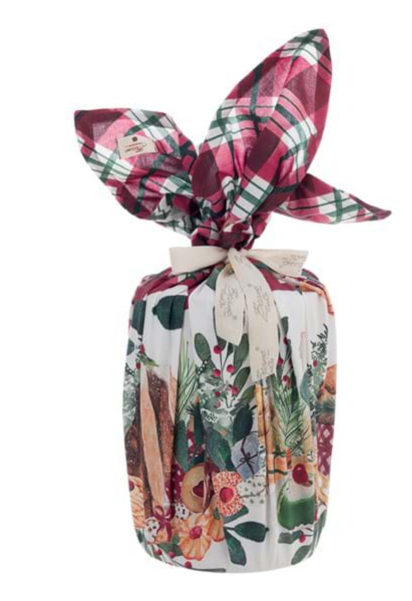 Foulard natalizio Blanc Mariclò serie "La Patisserie" annodato intorno a un panettone. Il tessuto presenta una ricca stampa di dolci tipici e ghirlande, rifinito da un nodo a fiocco e un nastro logato color panna.