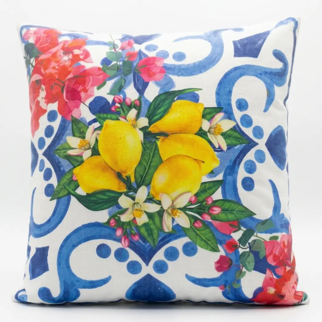 Cuscino decorativo caratterizzato da una vivace stampa in stile maiolica nei toni del bianco e del blu, arricchita al centro da un rigoglioso mazzo di limoni gialli con foglie verdi e fiori d'arancio. Gli angoli di questo cuscino quadrato sono impreziositi da eleganti composizioni di fiori rosa e fucsia, rendendolo l'accessorio ideale per donare un fresco tocco mediterraneo a divani, poltrone o letti.