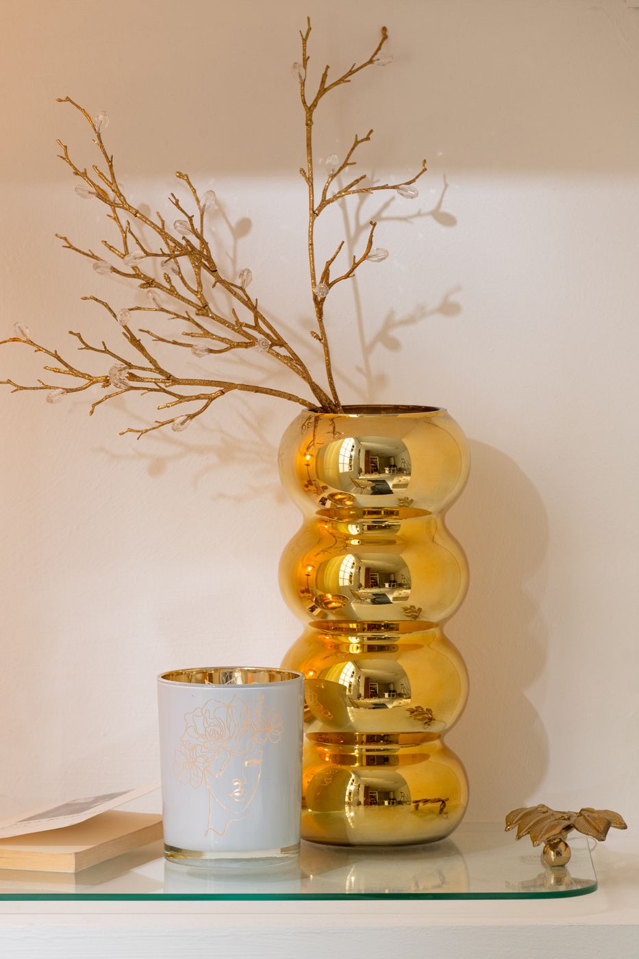 Vaso Bruco dorato con una lussuosa finitura metallica lucida a effetto specchio, caratterizzato da uno sviluppo verticale slanciato e un design moderno a quattro moduli sferici sovrapposti. Questo elegante complemento d'arredo per interni si sviluppa con una caratteristica forma sagomata a onde, ideale sia come vaso per fiori a stelo lungo sia come elemento decorativo di design per impreziosire la casa.
