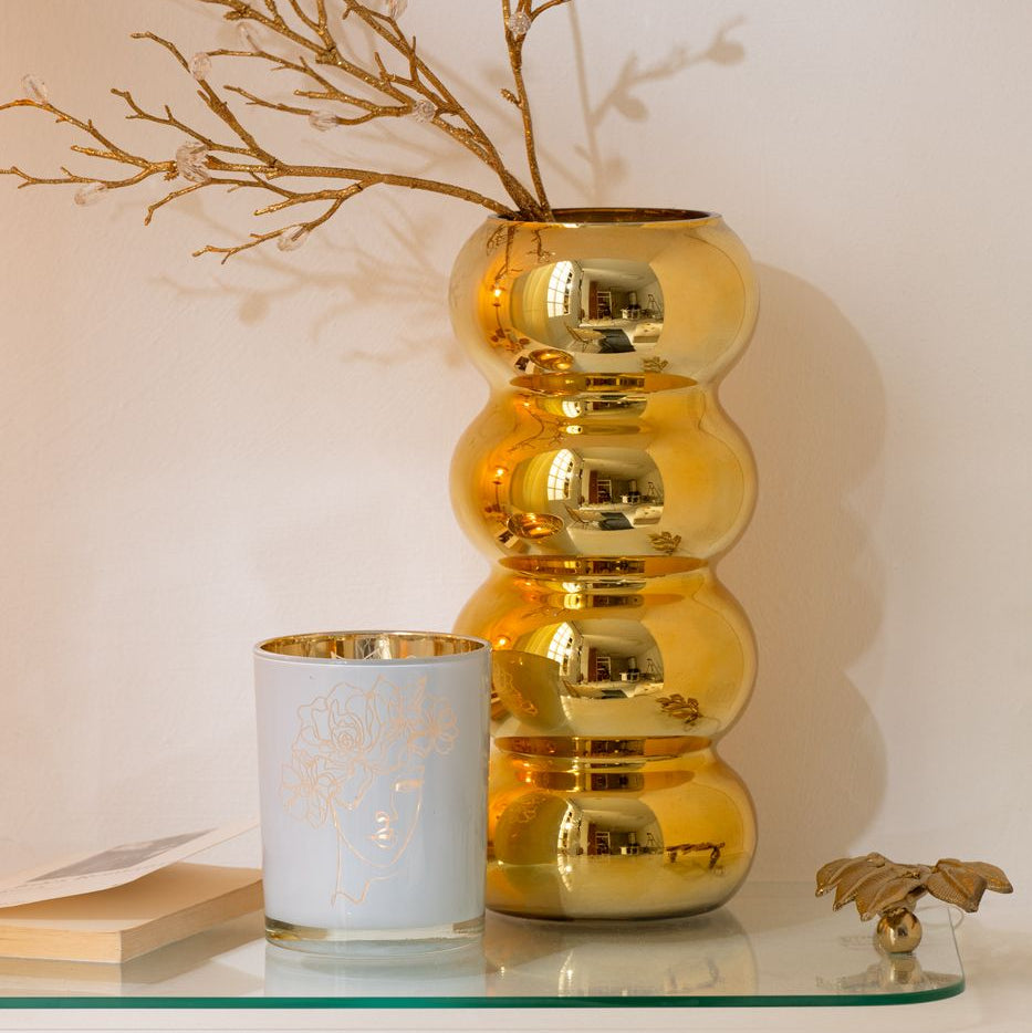 Vaso Bruco dorato con una lussuosa finitura metallica lucida a effetto specchio, caratterizzato da uno sviluppo verticale slanciato e un design moderno a quattro moduli sferici sovrapposti. Questo elegante complemento d'arredo per interni si sviluppa con una caratteristica forma sagomata a onde, ideale sia come vaso per fiori a stelo lungo sia come elemento decorativo di design per impreziosire la casa.