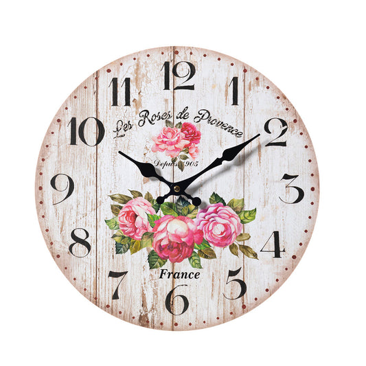 Un primo piano dell'orologio da parete artigianale de L'arte dei nacchi caratterizzato da un quadrante decorato con delicate rose sfumate e un'elegante scritta in corsivo. Questo complemento d'arredo unisce design romantico e stile shabby chic, rendendolo un elemento decorativo distintivo per valorizzare le pareti della casa con un tocco di artigianato italiano.