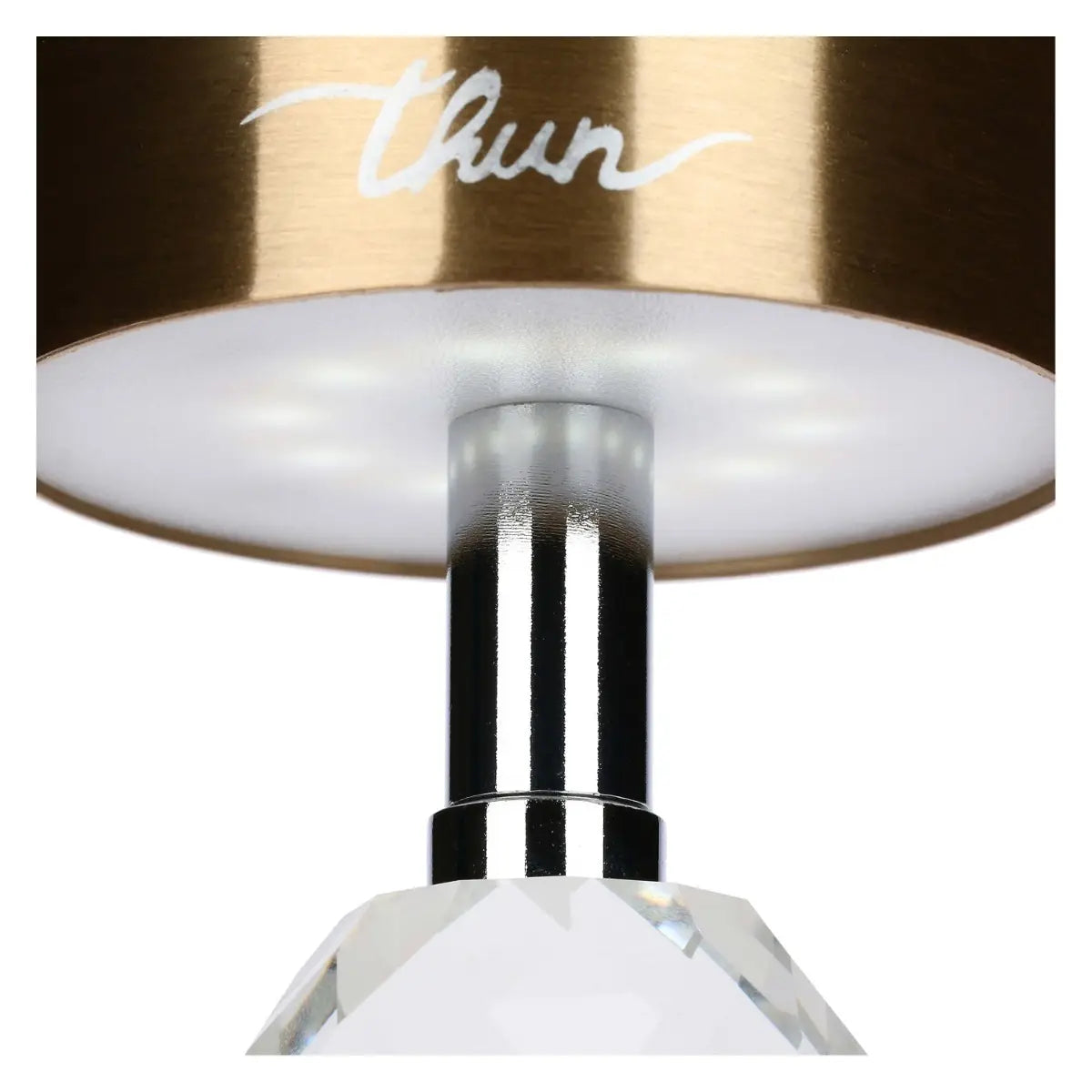 Inquadratura dal basso del paralume oro che mostra il pannello LED circolare acceso, il quale emette una luce calda attraverso il diffusore bianco. Sono visibili anche la porta USB-C, lo stelo cromato e la parte superiore del cristallo bianco.