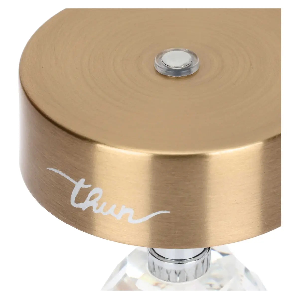 Vista ravvicinata dall'alto del paralume oro; al centro della parte superiore è visibile un piccolo pulsante metallico circolare con bordo trasparente, utilizzato per l'accensione e la regolazione.