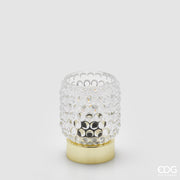 La lampada da tavolo Bubbles di Enzo De Gasperi (EDG) si distingue per un design raffinato che unisce un diffusore in vetro trasparente con un caratteristico motivo a rilievo a bolle e una base cilindrica in metallo dalla finitura dorata lucida. La particolare lavorazione del vetro permette alla luce di rifrangersi nell'ambiente in modo suggestivo, rendendo l'oggetto ideale come punto luce d'accento per spazi in stile Modern Luxury o Glamour.