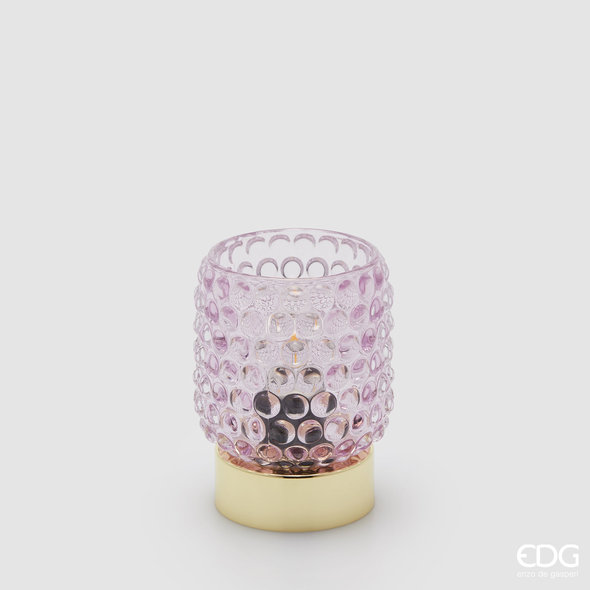La lampada da tavolo Bubbles di Enzo De Gasperi (EDG) si distingue per un design raffinato che unisce un diffusore in vetro trasparente rosa con un caratteristico motivo a rilievo a bolle e una base cilindrica in metallo dalla finitura dorata lucida. La particolare lavorazione del vetro permette alla luce di rifrangersi nell'ambiente in modo suggestivo, rendendo l'oggetto ideale come punto luce d'accento per spazi in stile Modern Luxury o Glamour.