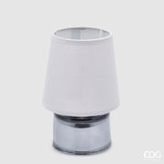 Piccola lampada da tavolo EDG Cozy color grigio blu, composta da un paralume in tessuto e una base cilindrica in vetro coordinati, posizionata su uno sfondo grigio neutro.