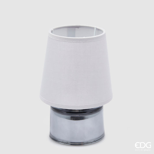 Piccola lampada da tavolo EDG Cozy color grigio blu, composta da un paralume in tessuto e una base cilindrica in vetro coordinati, posizionata su uno sfondo grigio neutro.