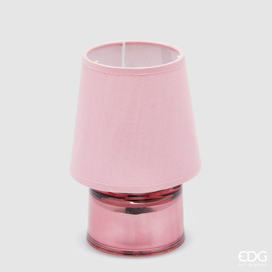 Piccola lampada da tavolo EDG Cozy color rosa pastello, composta da un paralume in tessuto e una base cilindrica in vetro coordinati, posizionata su uno sfondo grigio neutro.