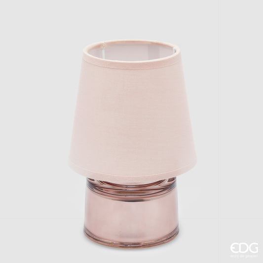 Piccola lampada da tavolo EDG Cozy color rosa pastello, composta da un paralume in tessuto e una base cilindrica in vetro coordinati, posizionata su uno sfondo grigio neutro.
