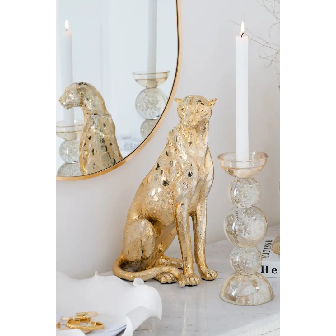 Statuina in poliresina dorata raffigurante un leopardo seduto in posizione eretta, con testa alta e coda avvolta lateralmente, superficie a effetto metallizzato con texture a macchie in rilievo. Scultura decorativa firmata Jolipa, ideale come oggetto d'arredo di design o idea regalo raffinata.