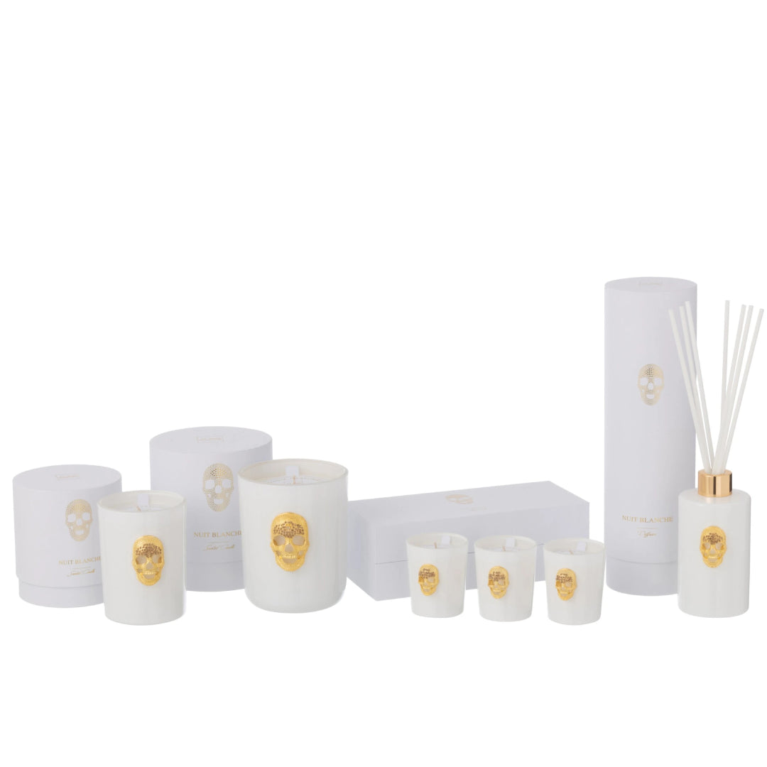 Collezione completa di candele profumate e diffusore d'ambiente a bastoncini della linea "Nuit Blanche" firmata Jolipa, caratterizzata da eleganti boccette e bicchieri in vetro bianco lucido impreziositi da un teschio dorato in rilievo. Questa esclusiva selezione di profumatori e candele decorative include scatole e confezioni regalo total white coordinate con dettagli in oro, perfetta come raffinata idea regalo o per impreziosire l'arredamento di interni moderni e di lusso.