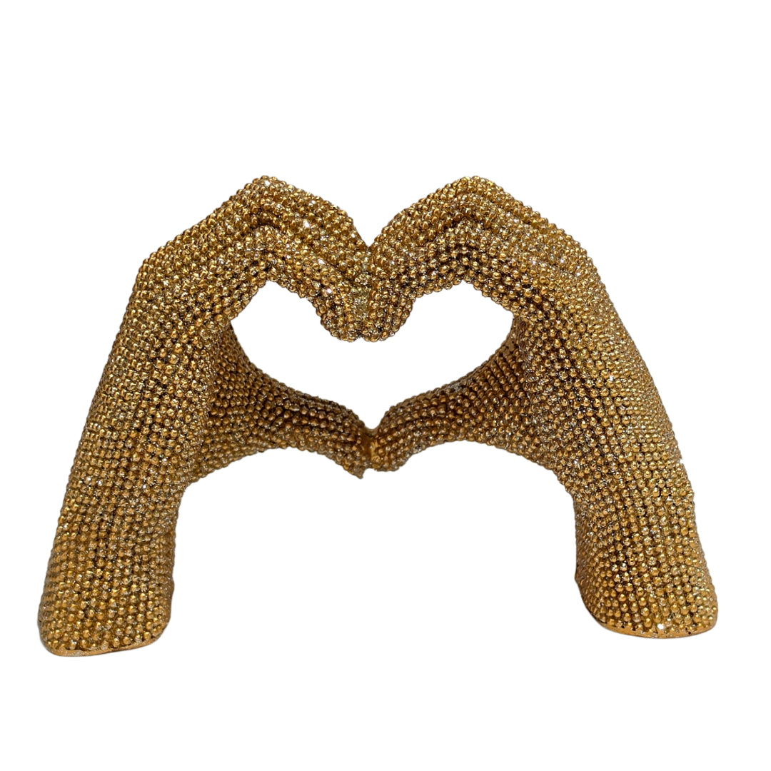 Statuina in resina raffigurante due mani dorate intrecciate a formare un cuore, interamente ricoperte di brillantini glitterati dall'effetto scintillante. Oggetto decorativo firmato Sud Import, ideale come soprammobile romantico o idea regalo per San Valentino e occasioni speciali.