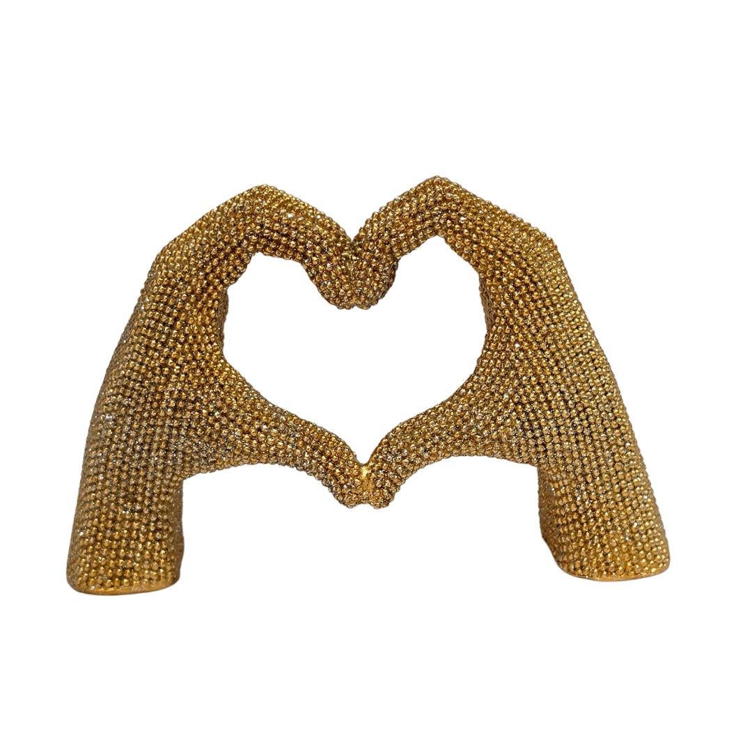 Statuina in resina raffigurante due mani dorate intrecciate a formare un cuore, interamente ricoperte di brillantini glitterati dall'effetto scintillante. Oggetto decorativo firmato Sud Import, ideale come soprammobile romantico o idea regalo per San Valentino e occasioni speciali.