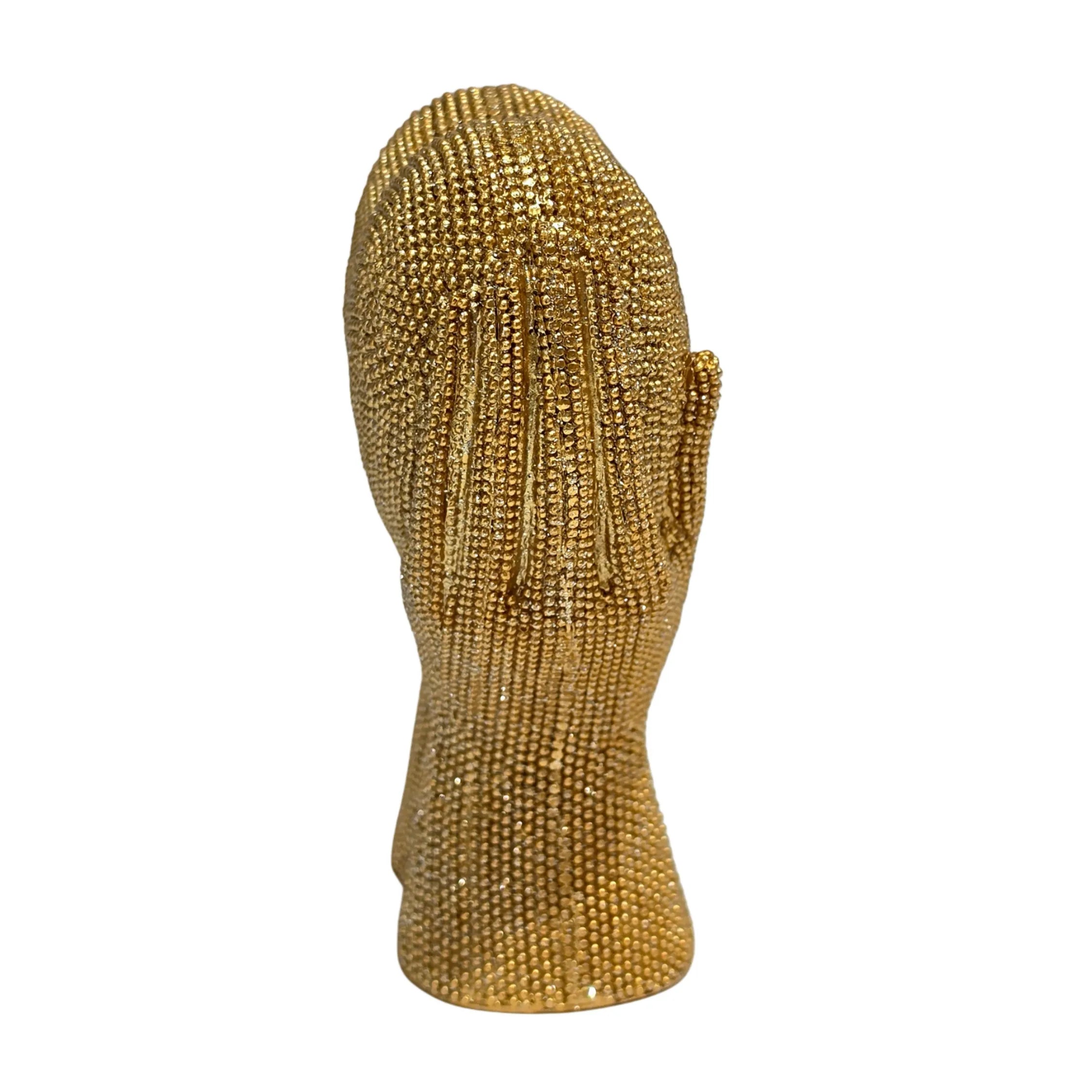 Statuina in resina raffigurante due mani dorate unite a formare un cuore visto frontalmente, interamente ricoperte di brillantini glitterati dall'effetto scintillante. Oggetto decorativo firmato Sud Import, ideale come soprammobile romantico o idea regalo per San Valentino e occasioni speciali.