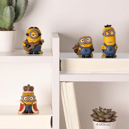 La collezione include diverse varianti dei celebri personaggi: Kevin con le mani dietro la schiena, Stuart con chitarra, Bob con orsetto di peluche e sempre Bob in versione "re" con corona e mantello, tutti esposti in un moderno contesto di home decor.