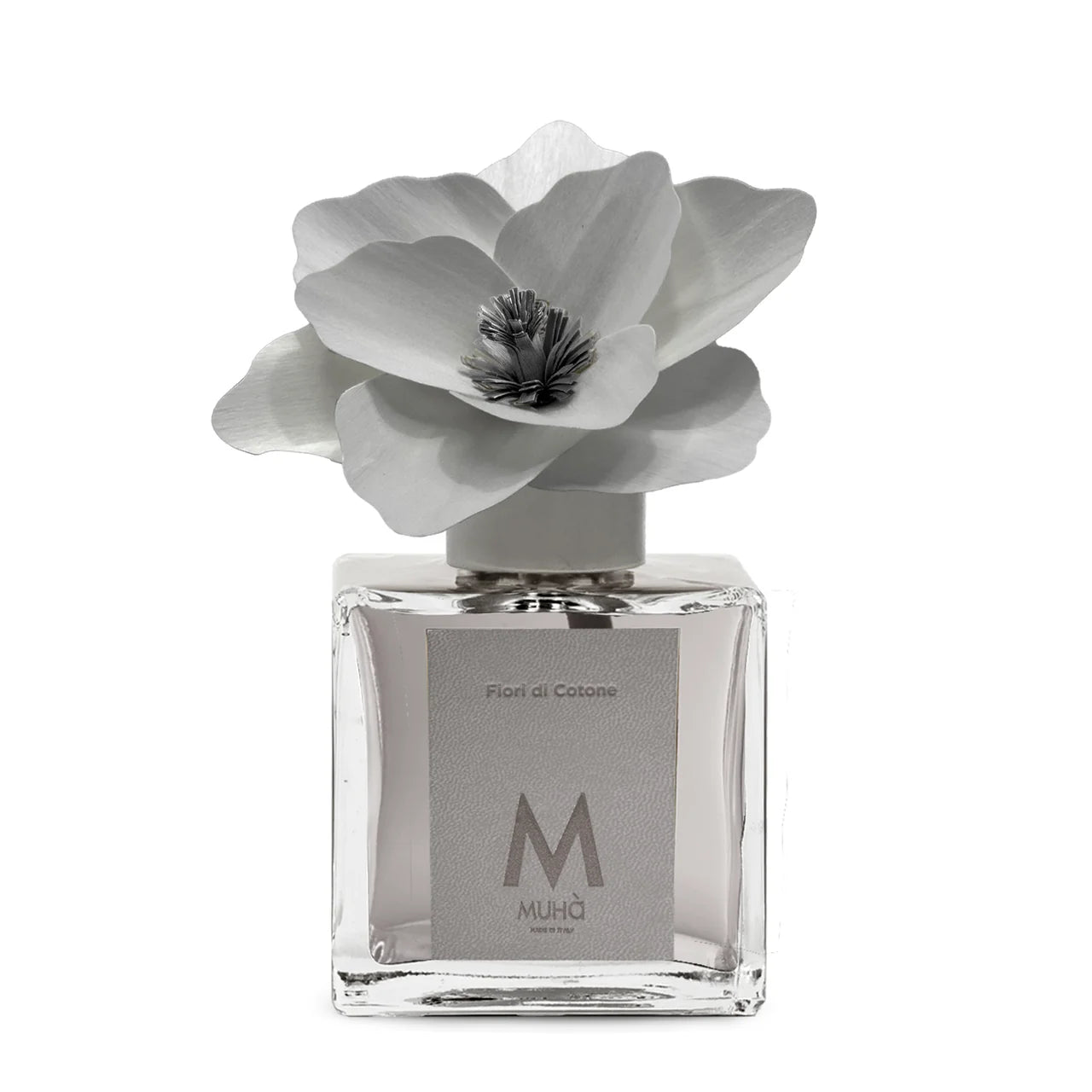Profumatore d'ambiente Muhà Magnolia: flacone quadrato in vetro trasparente con essenza Fiori di Cotone e scenografico fiore in betulla color grigio.