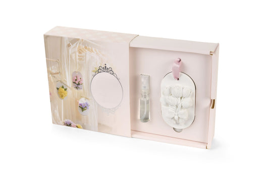 Gessetto profumato da appendere della collezione "Fiorirà" di Nuvole di Stoffa, caratterizzato da una placchetta ovale bianca decorata con un bouquet di tulipani in rilievo e un nastrino rosa. Il set include una boccetta di profumo spray concentrato ed è presentato in un'elegante confezione a cassetto nei toni del rosa pastello, ideale come bomboniera o profumatore per armadi e cassetti.