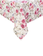 Inquadratura ravvicinata dell'angolo di una tovaglia beige con stampa floreale di peonie rosa e fucsia. Il tessuto cade morbidamente mostrando il pattern continuo di fiori e foglie grigie e lilla.