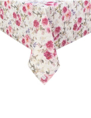 Inquadratura ravvicinata dell'angolo di una tovaglia beige con stampa floreale di peonie rosa e fucsia. Il tessuto cade morbidamente mostrando il pattern continuo di fiori e foglie grigie e lilla.